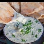 Weight Watchers Tzatziki Sauce in a black dip bowl, with a pita chip being dipped into it.