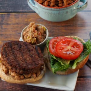 Maple Baked Bean and Jalapeno Aioli on a hamburger, with more on the side and maple baked beans in the background.