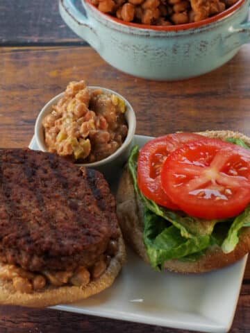 Maple Baked Bean and Jalapeno Aioli on a hamburger, with more on the side and maple baked beans in the background.