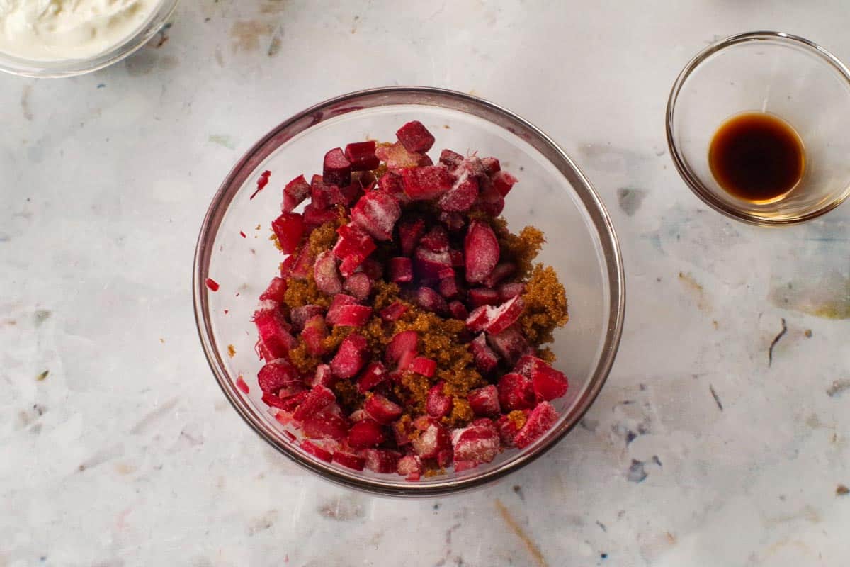 Rhubarb, water, and brown sugar mixed together in a microwave-safe bowl. 