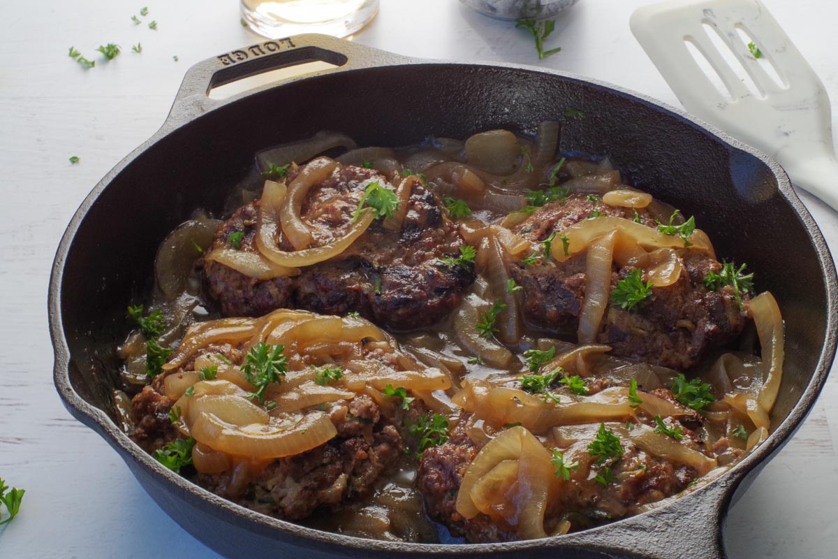 Grilled healthy Salisbury Steak with Beer and Onion Gravy in a cast iron pan