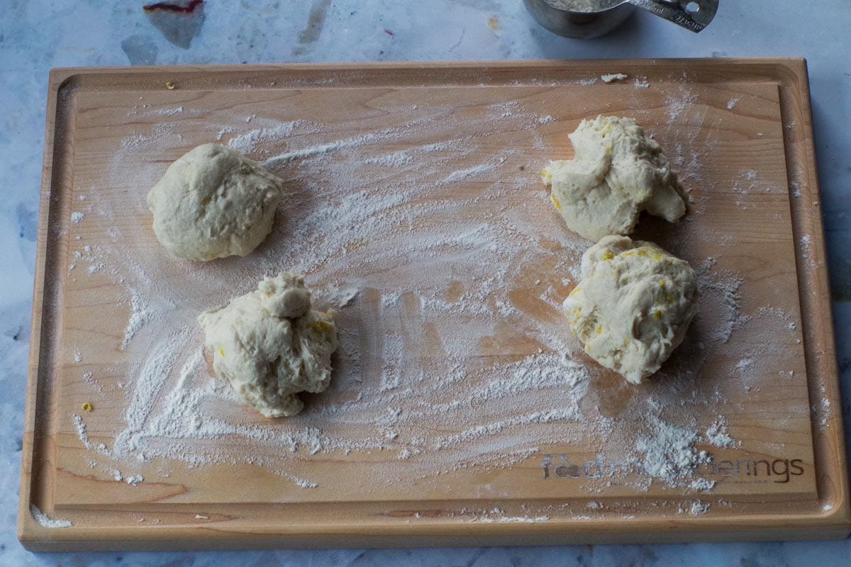Healthy Beaver Tail Dough divided into 4 sections on floured wooden cutting board.