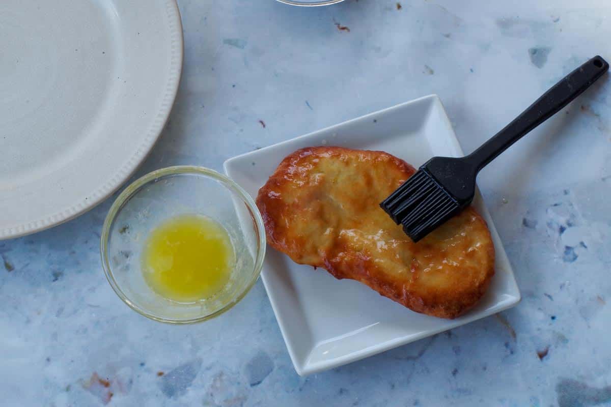 Cooked Air Fryer Beaver Tails being brushed with butter with a black silicone pastry brush.