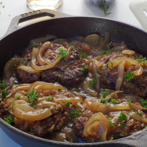 Grilled healthy Salisbury Steak with Beer and Onion Gravy in a cast iron pan