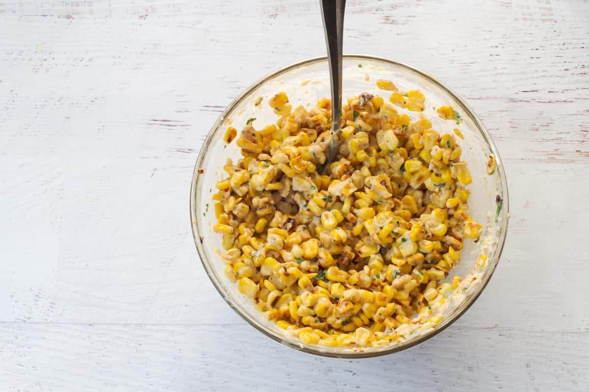 Corn and sauce mixed together in a glass bowl.