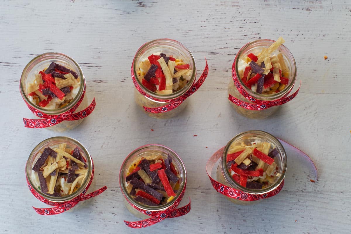 Tortilla strips added to jars on top of feta cheese.
