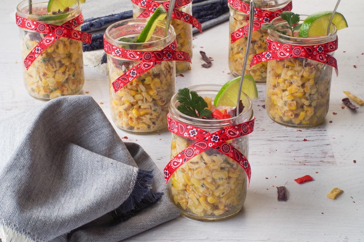 Stampede Street Corn Cup with a denim napkin beside it and 5 more corn cups in the background.