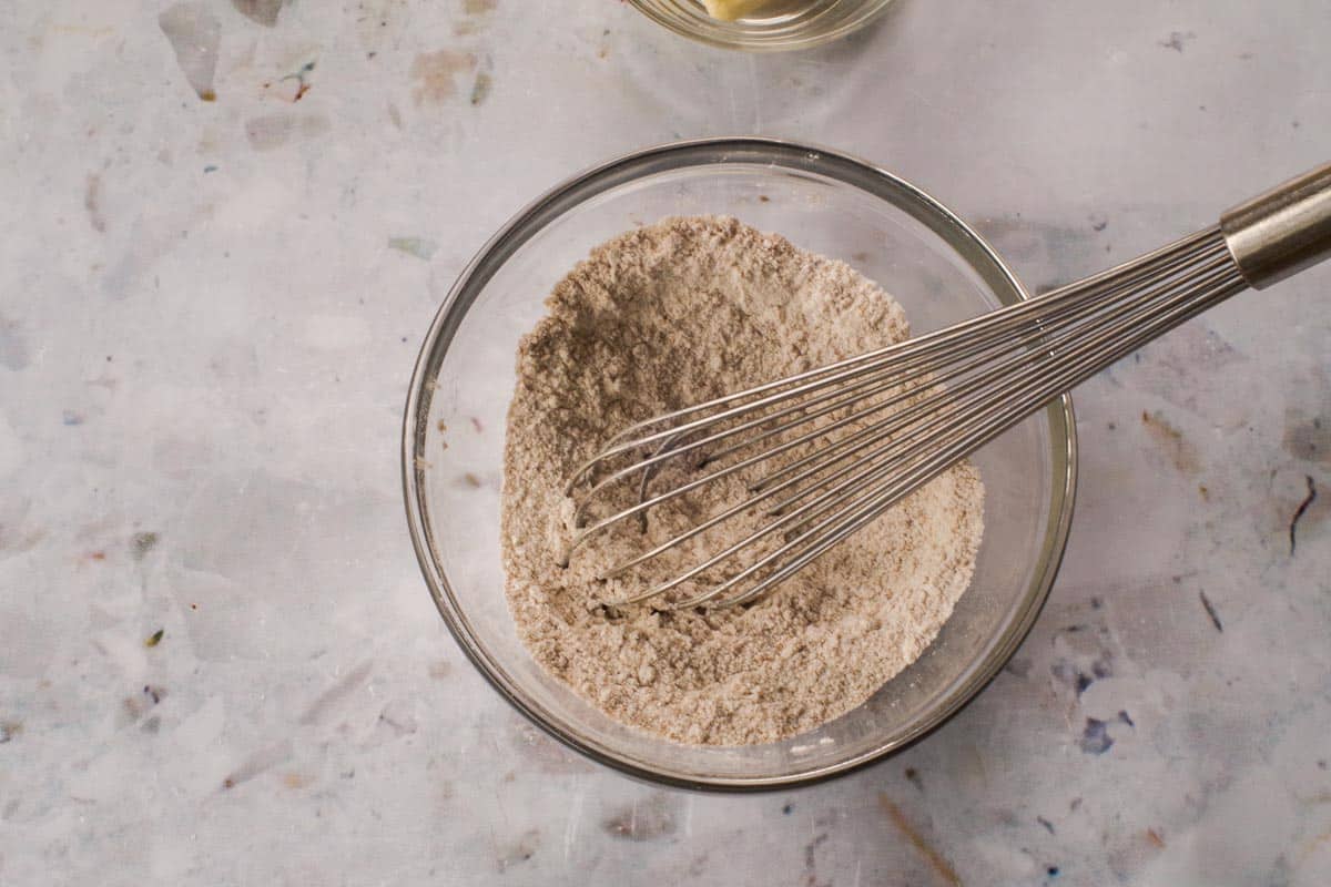 Dry topping ingredients mixed together in a glass bowl with a metal whisk.