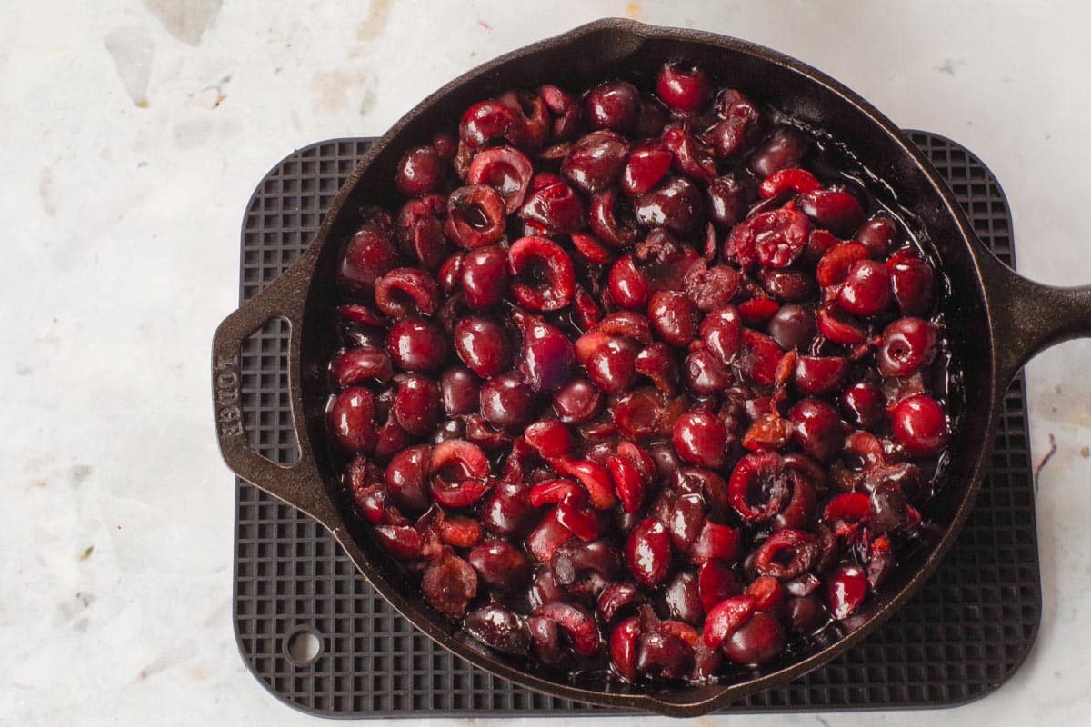 Precooked cherries in a cast iron frying pan.