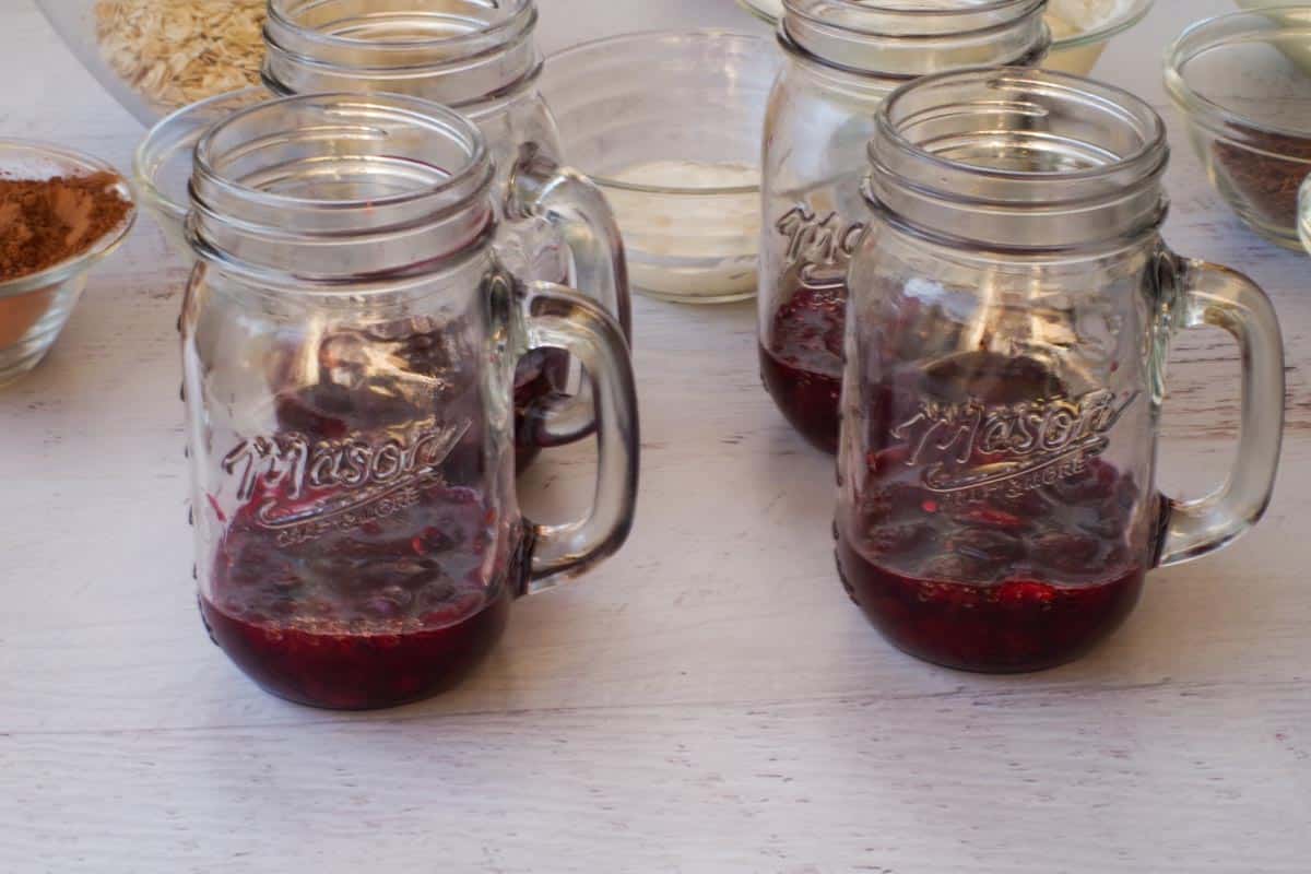 Mashed cherry mixture divided by 4 mason jars.