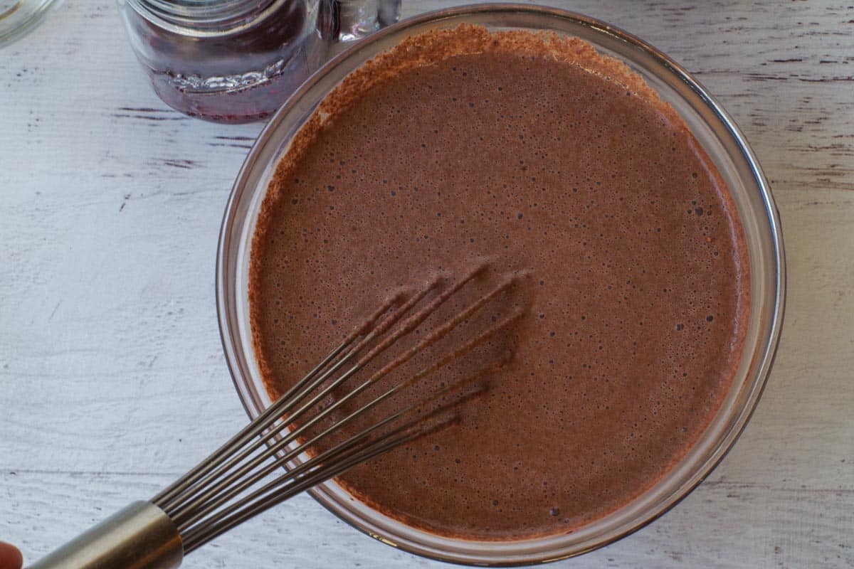 Cocoa, Greek yogur and milk whisked together in glass bowl.