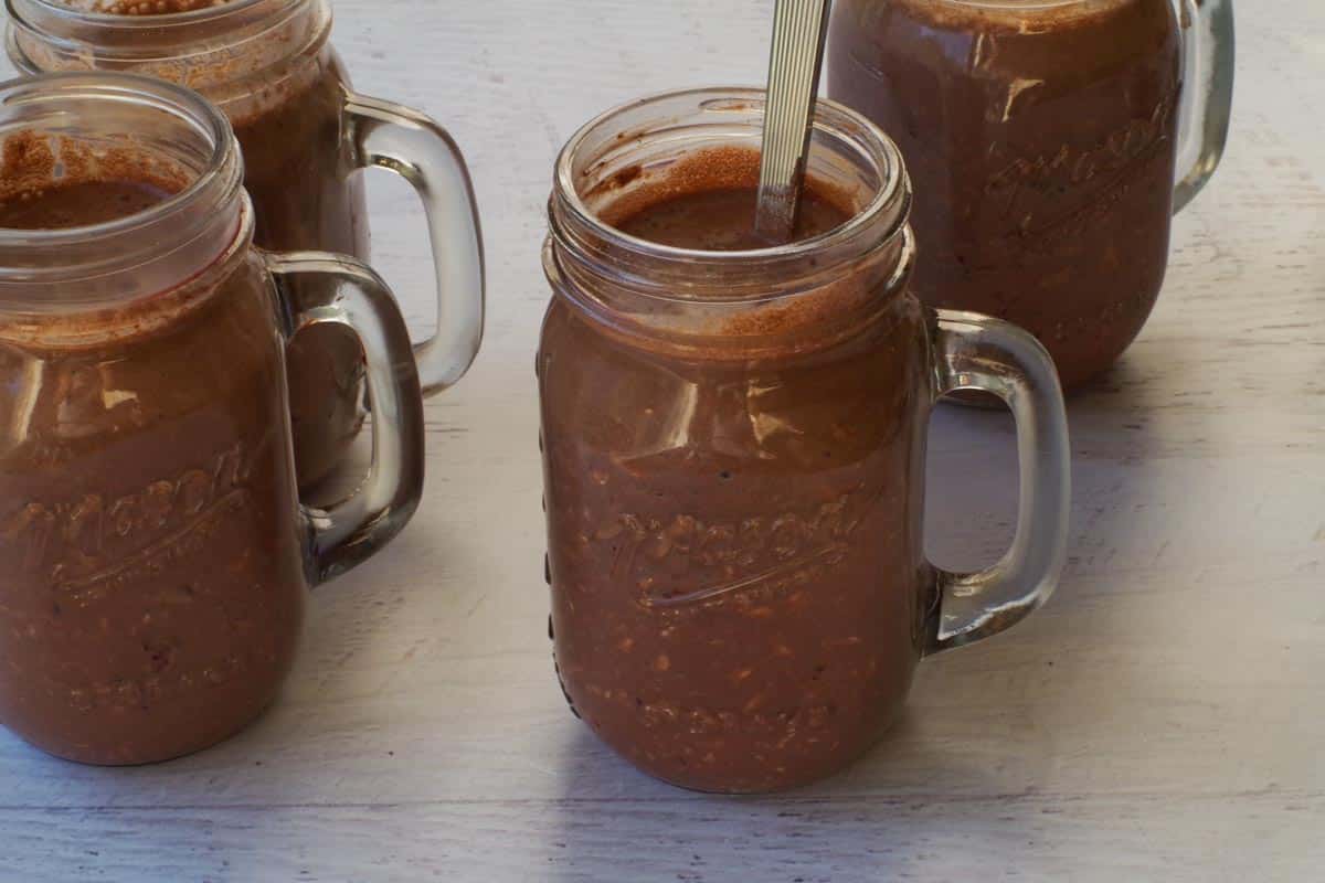 Healthy Black Forest Overnight Oats being stirred vigorously in jars.