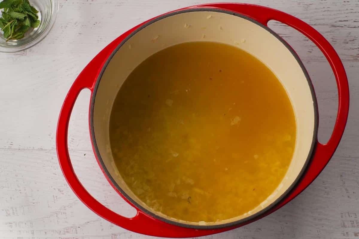 Chicken broth added to rice and onion in Dutch oven.