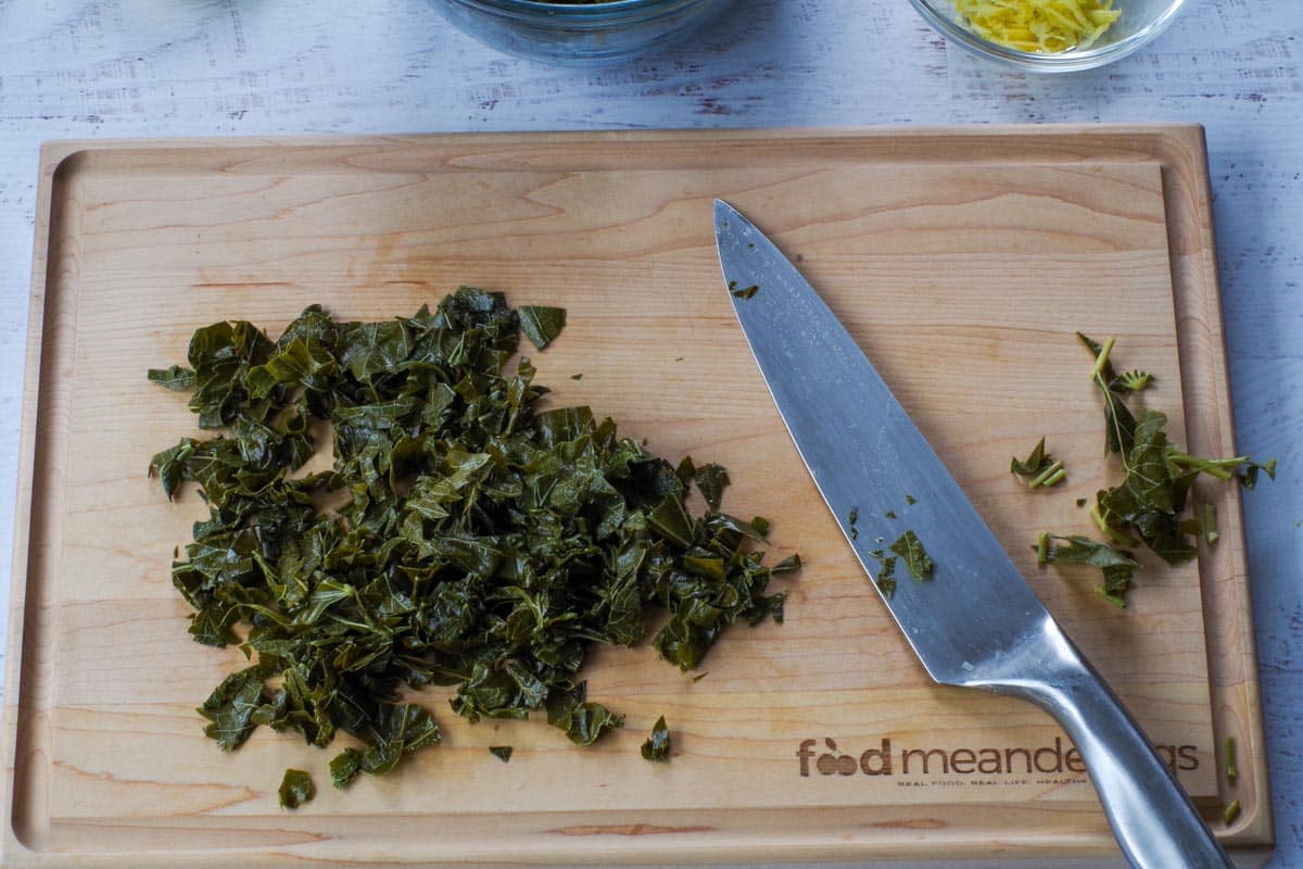 Grape leaves chopped into small pieces on a wooden cutting board.