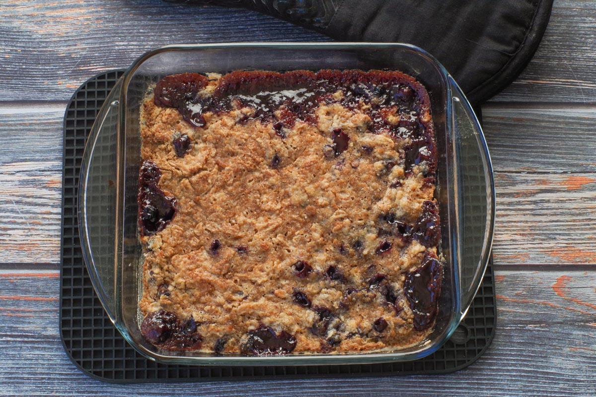 Baked Saskatoon Berry Crumble reicpe in square glass pan on black trivet.