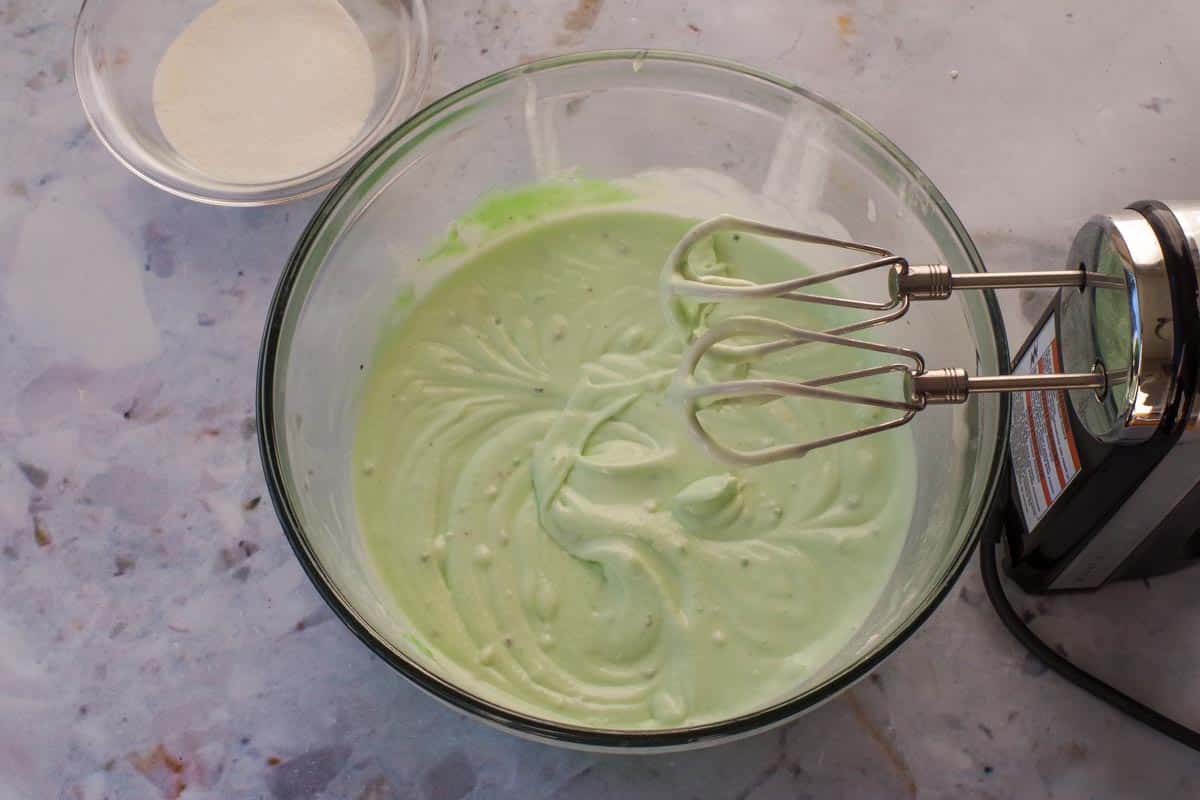 Softened ice cream and pistachio pudding beaten together in a large glass bowl.