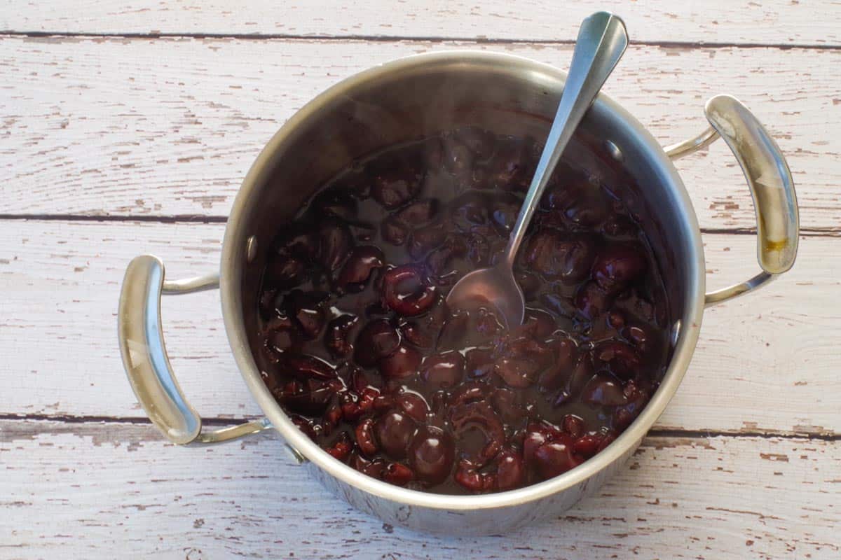 Thickened Fresh Cherry Sauce in pot with spoon.