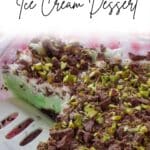 Pistachio Ice Cream Dessert in a 9x13 glass poan with 2 pieces missing and a spatula in that space in the pan.