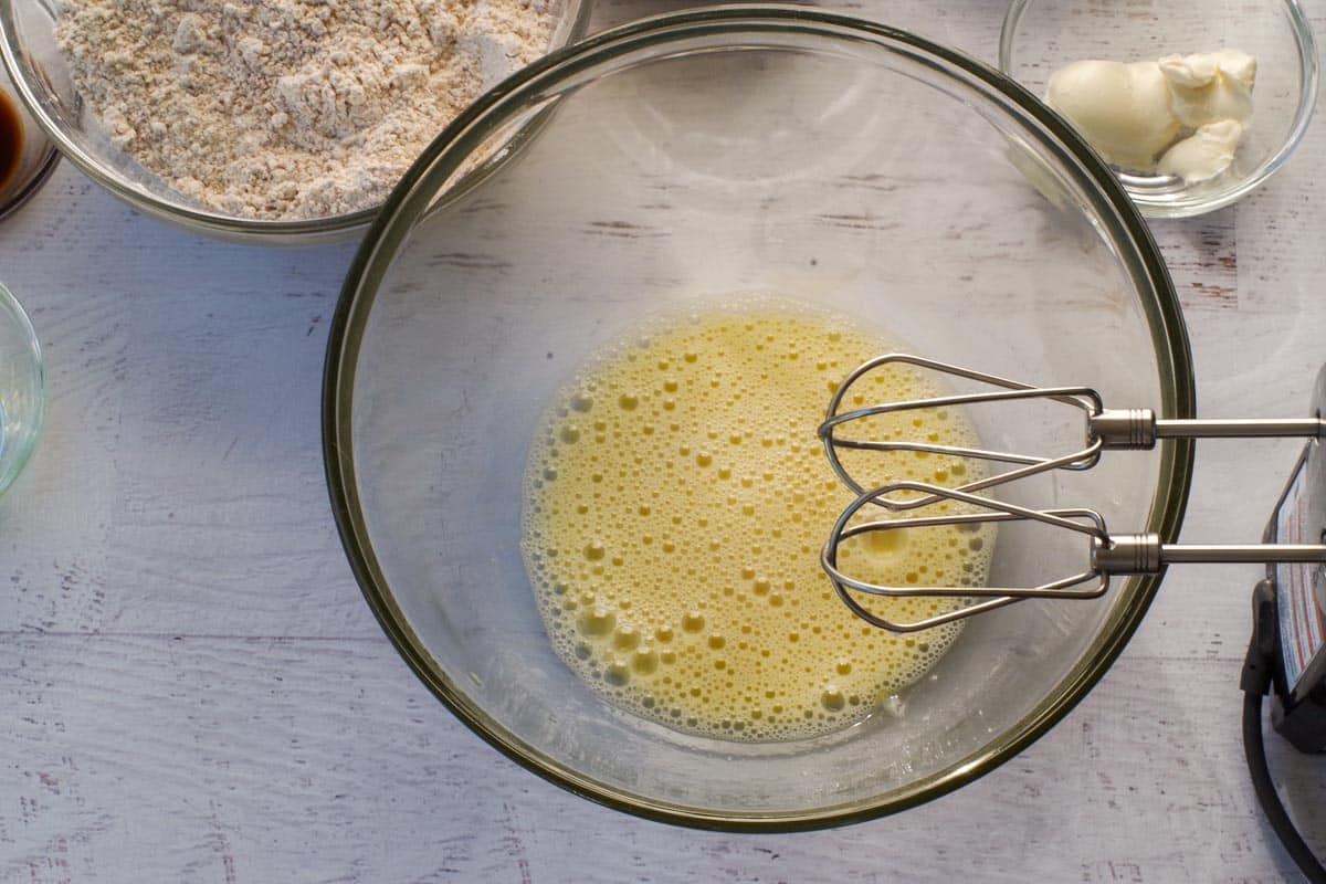 Egg beaten with electric mixer in large glass bowl.