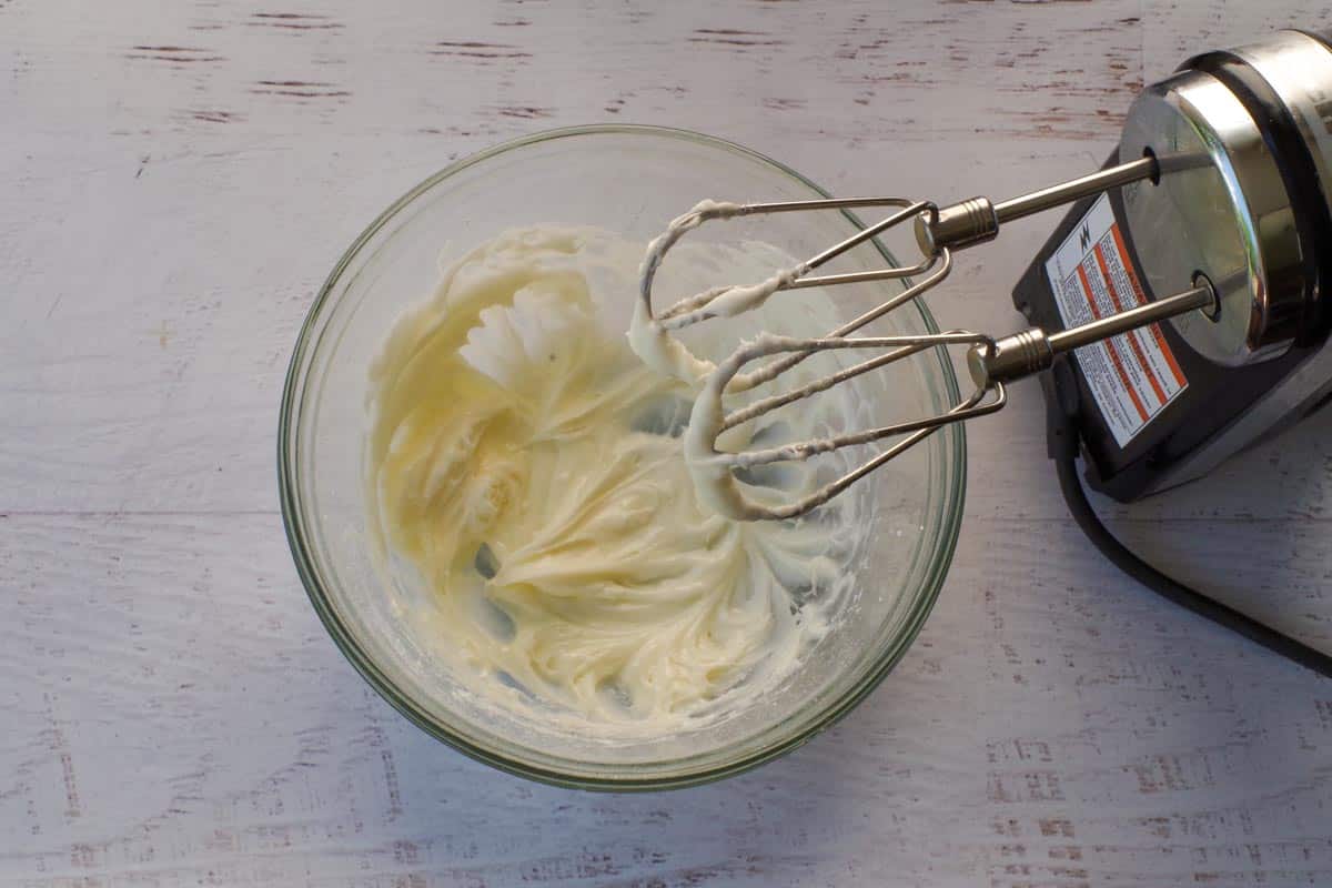 Cream cheese and powdered sugar beaten together in large glass bowl with electric mixer.