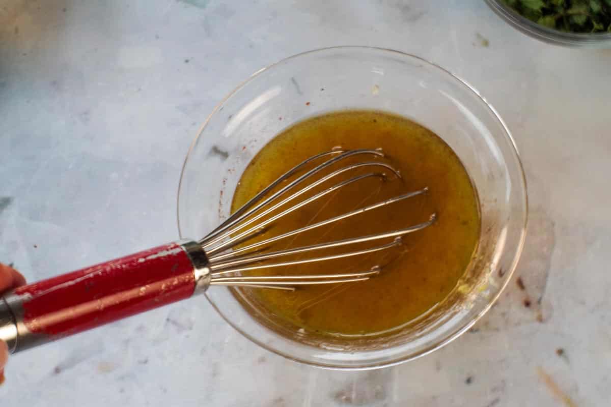 Lemon juice, lemon zest, oil and spices mixed together in small glass bowl.