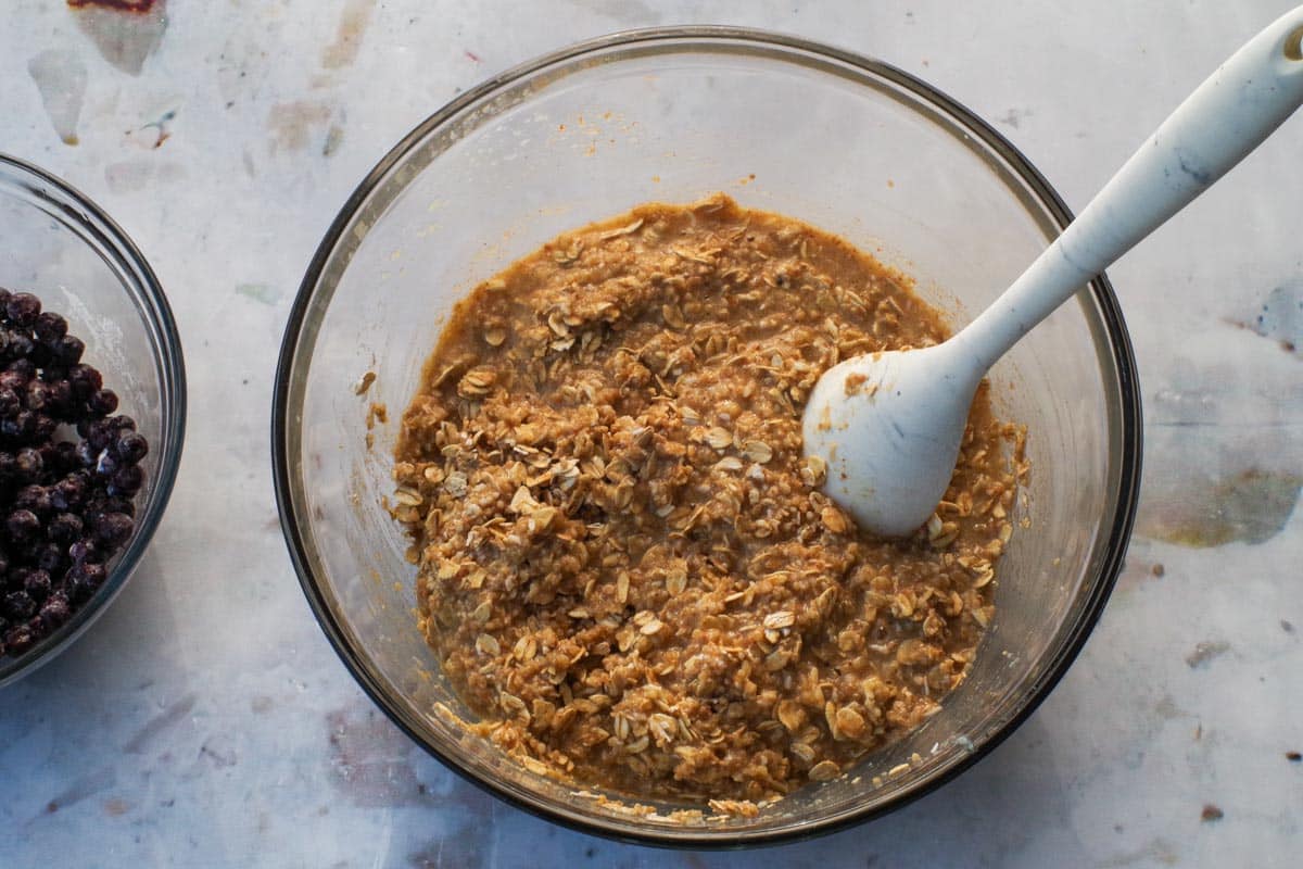 Dry ingredients in Healthy Saskatoon Berry Oatmeal Bars stirred into the wet ingredients in a large glass bowl.