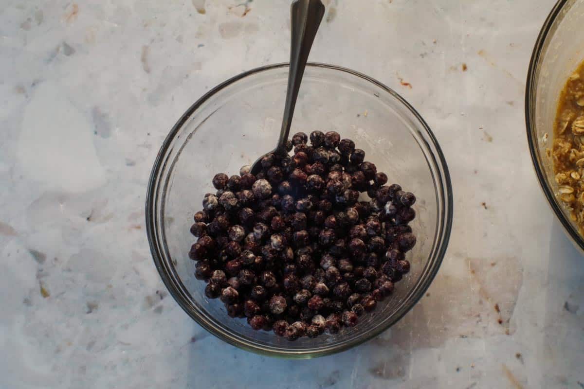 Saskatoon berries mixed with a teaspoon of flour in medium glass bowl.
