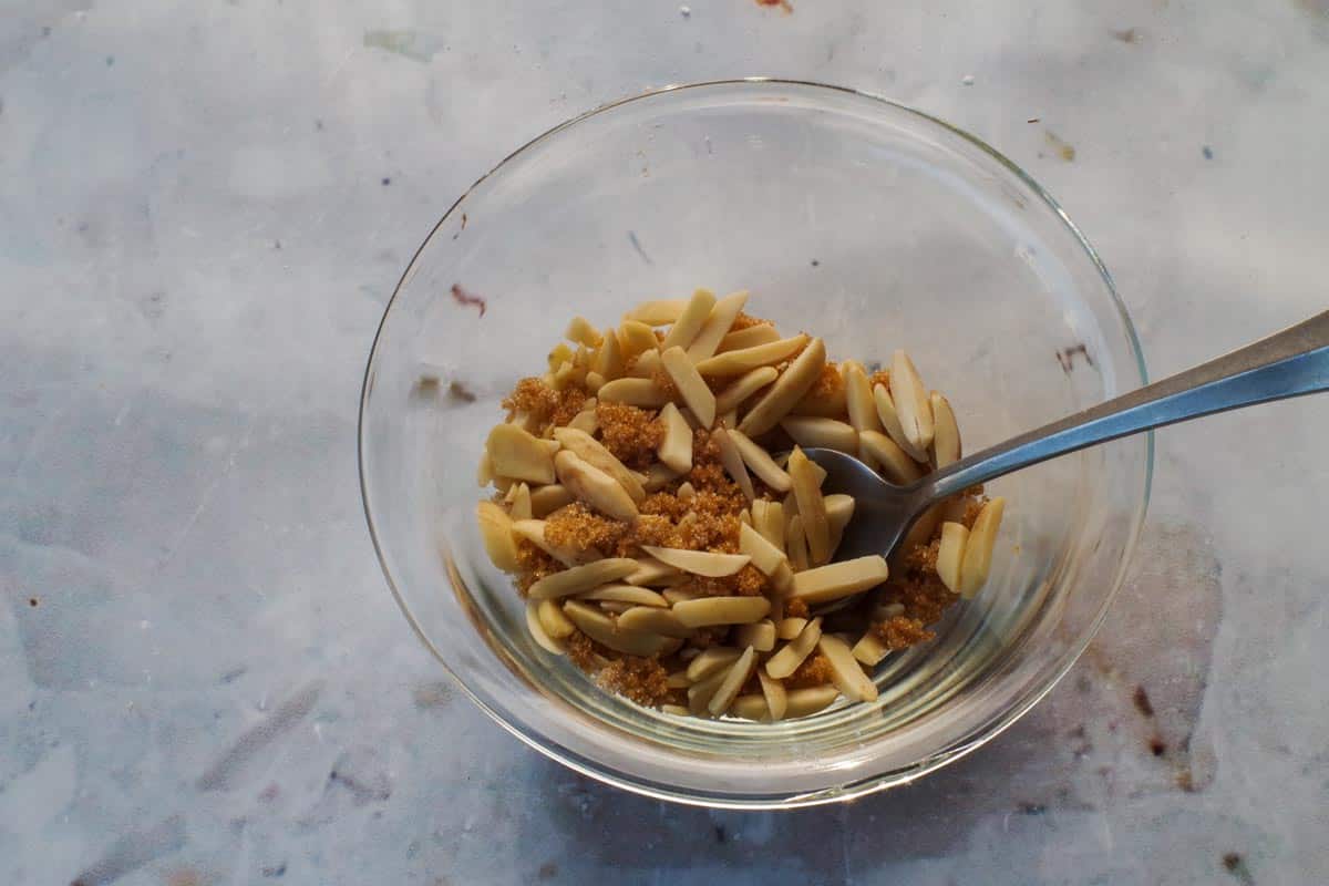 Remaining brown sugar, slivered almonds and white sugar mixed together in a small glass bowl, for the topping on the Healthy Saskatoon Berry Oatmeal Bars.