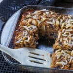 Healthy Sasktoon Berry Oatmeal Bars in an 8x8 glass pan with several pieces missing and a white spatula in the pan.