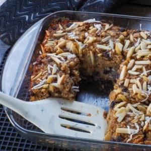 Healthy Sasktoon Berry Oatmeal Bars in an 8x8 glass pan with several pieces missing and a white spatula in the pan.