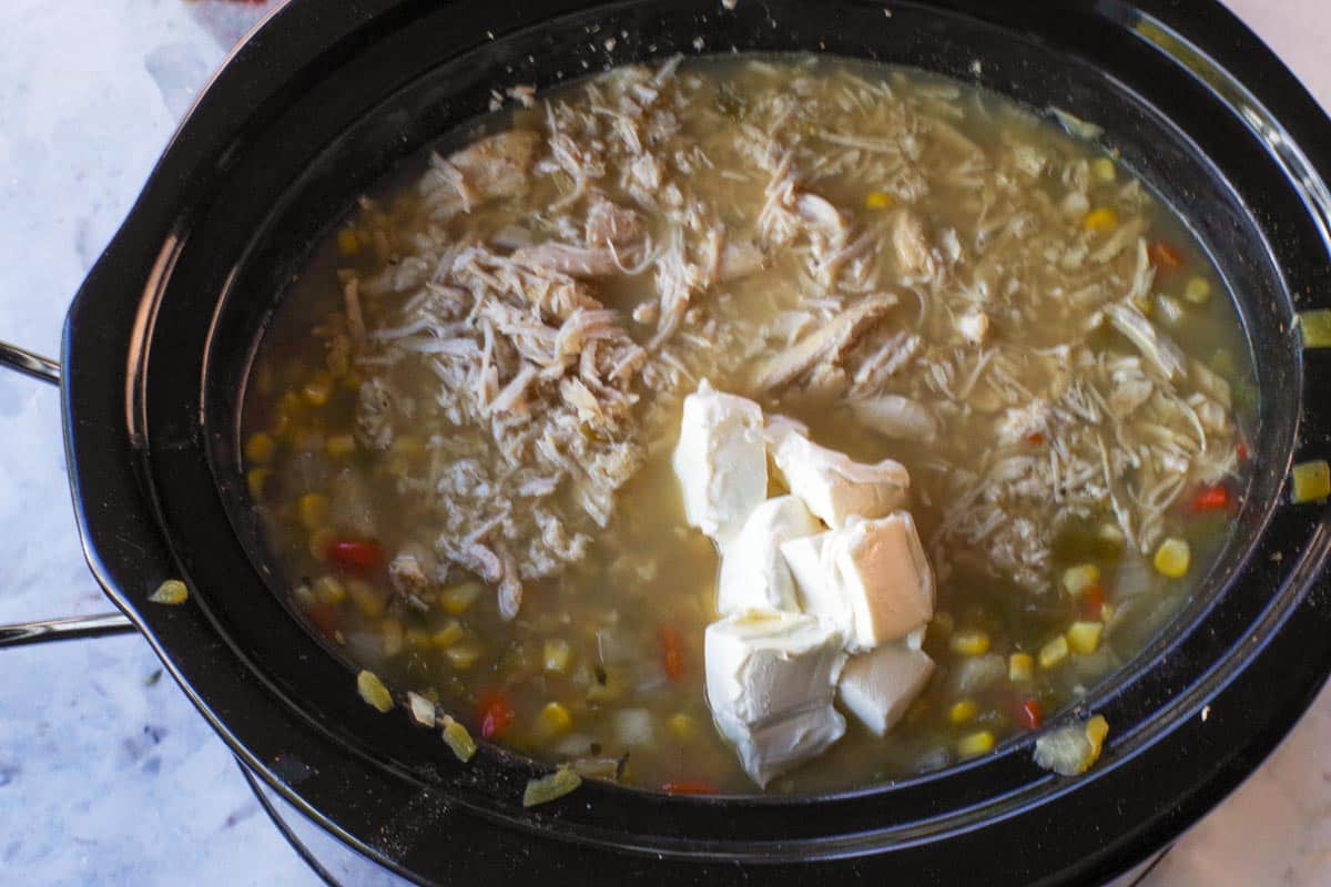 Chicken and cream cheese added to slow cooker.