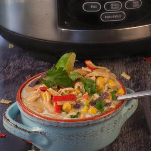 Healthy Creamy Crockpot White Chicken Chili in a bowl, in front of a slow cooker.