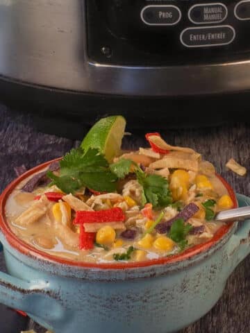 Healthy Creamy Crockpot White Chicken Chili in a bowl, in front of a slow cooker.