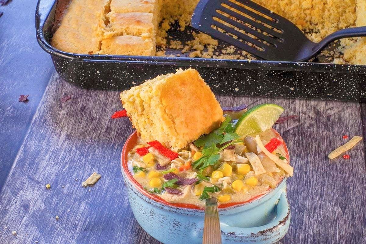 A piece of Old Fashioned Country Cornbread on a bowl of White Chicken Chili.