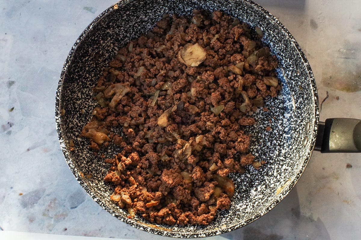 Beef. onions and mushrooms being sauteed in a pan.