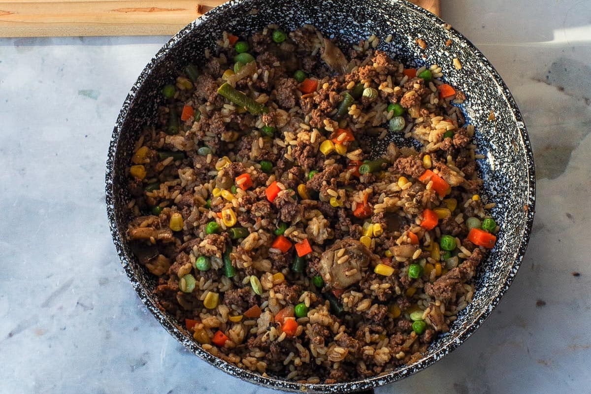 Gravy, vegetables and ketchup added to the sauteed beef mixture.