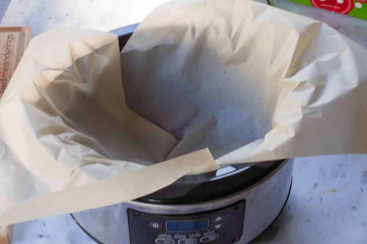 Parchment lined slow cooker with water in the bottom.